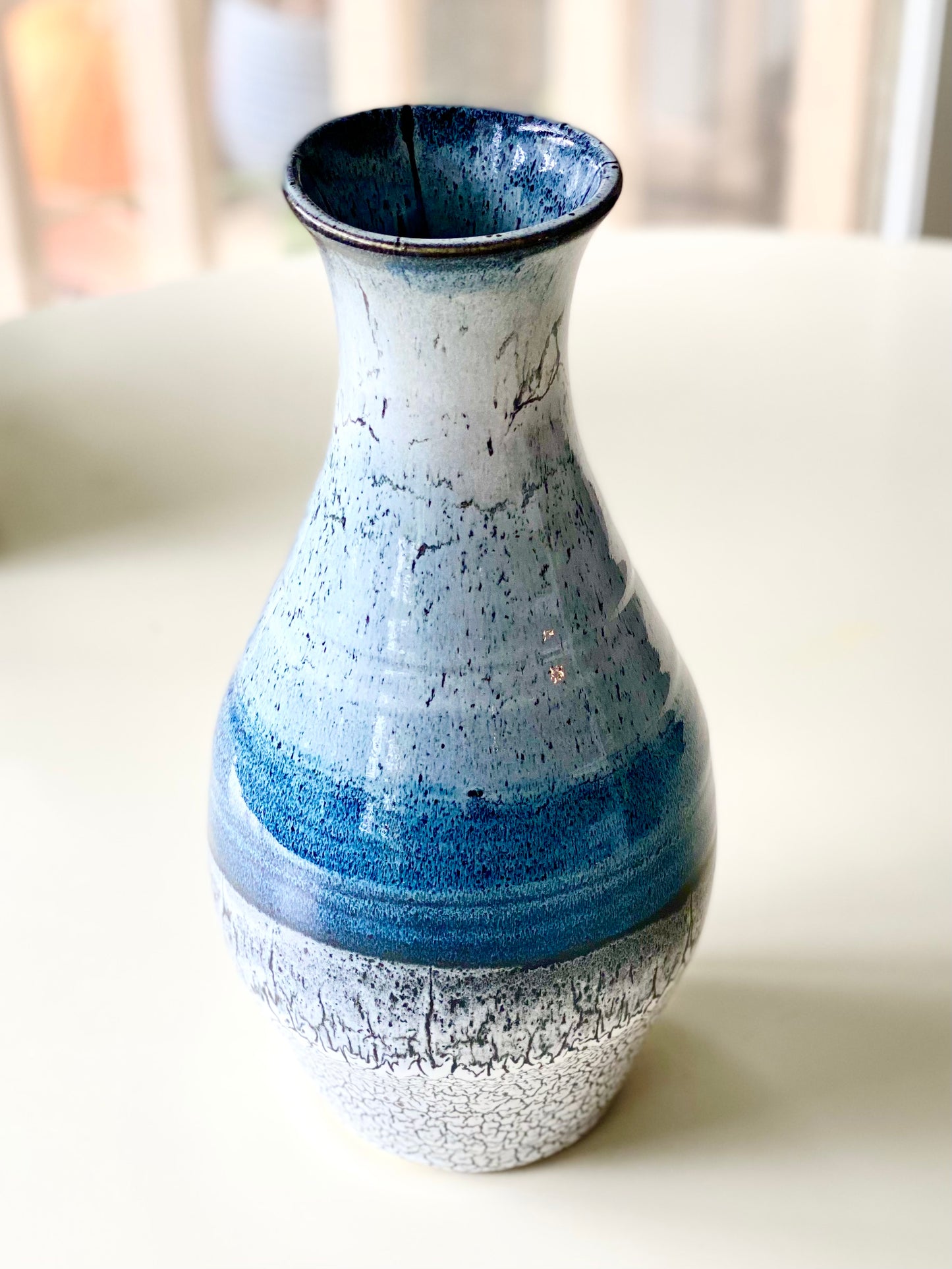 Vase 10.75”, A tall, elegant handmade vase with soft gradient glazes of sky blue, deep ocean blue, black, and crackled white (discounted for small crack underneath, normally $125)