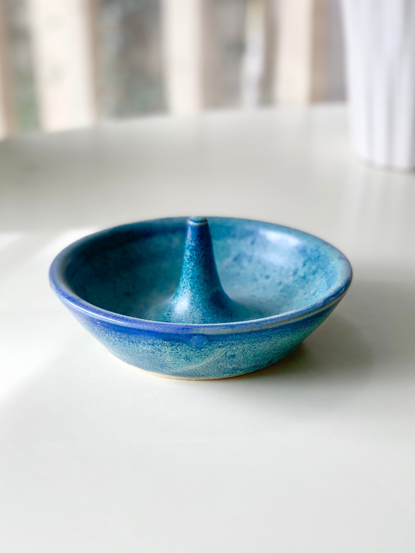 Ring Dish with a speckled ocean-blue glaze and a smooth center ring stem