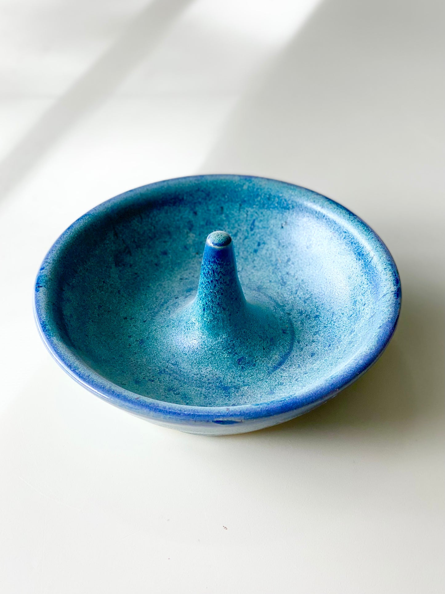 Ring Dish with a speckled ocean-blue glaze and a smooth center ring stem