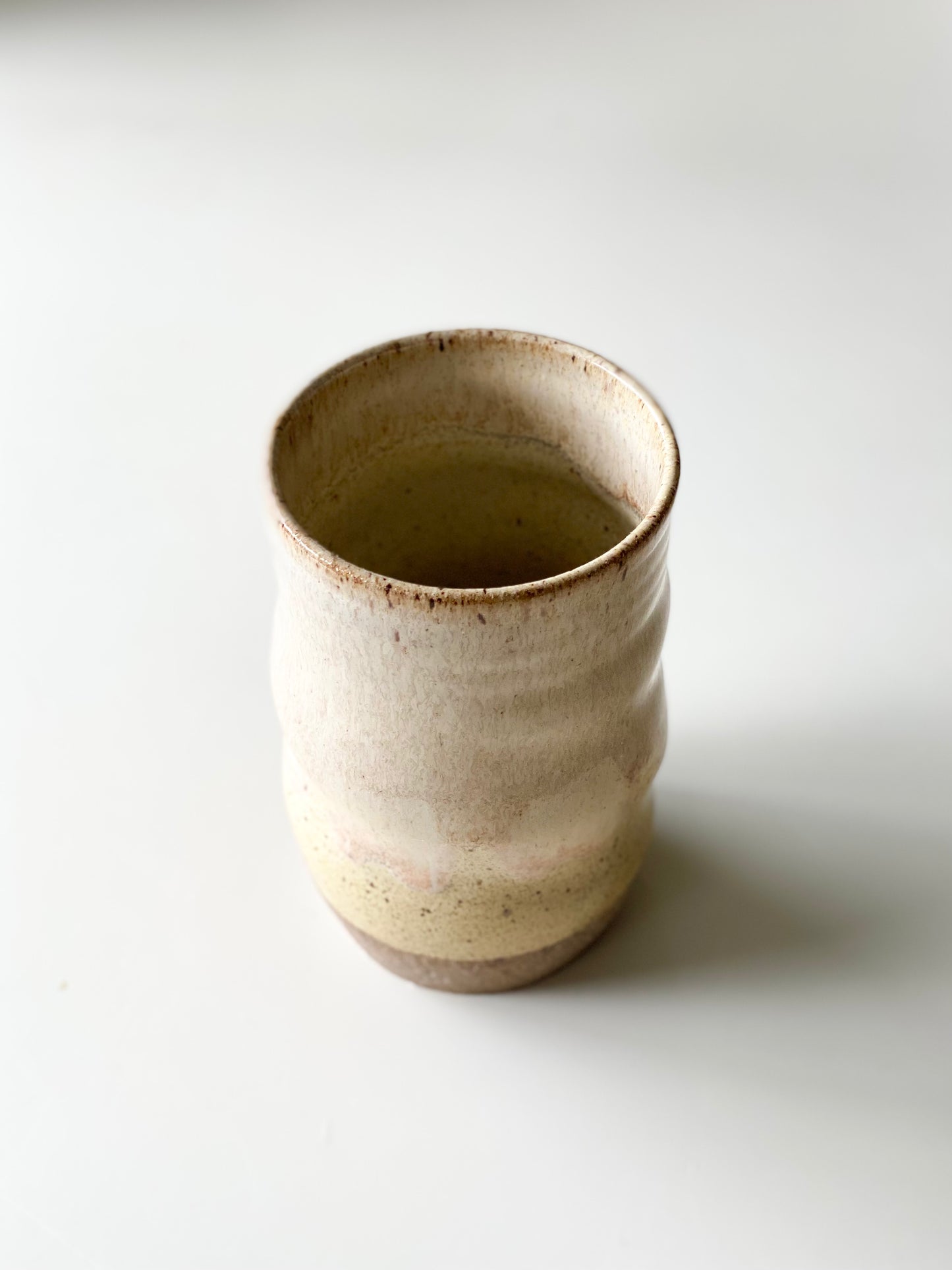 Tumbler, 16oz, no.19, A soft creamy white glaze fading into warm butter yellow with a blush of pink at the transition, breaking gently over the rustic, sandy clay base.
