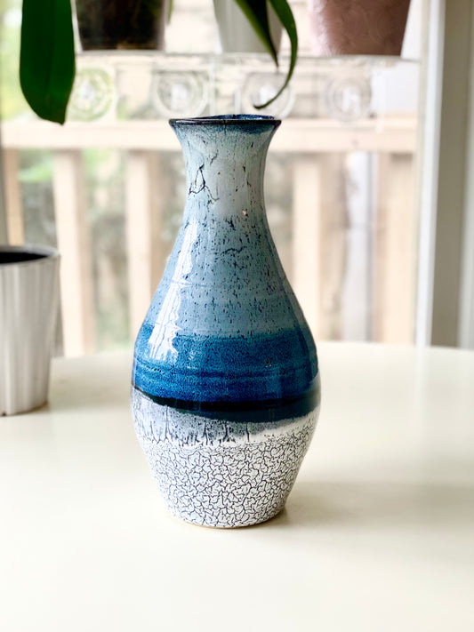 Vase 10.75”, A tall, elegant handmade vase with soft gradient glazes of sky blue, deep ocean blue, black, and crackled white (discounted for small crack underneath, normally $125)